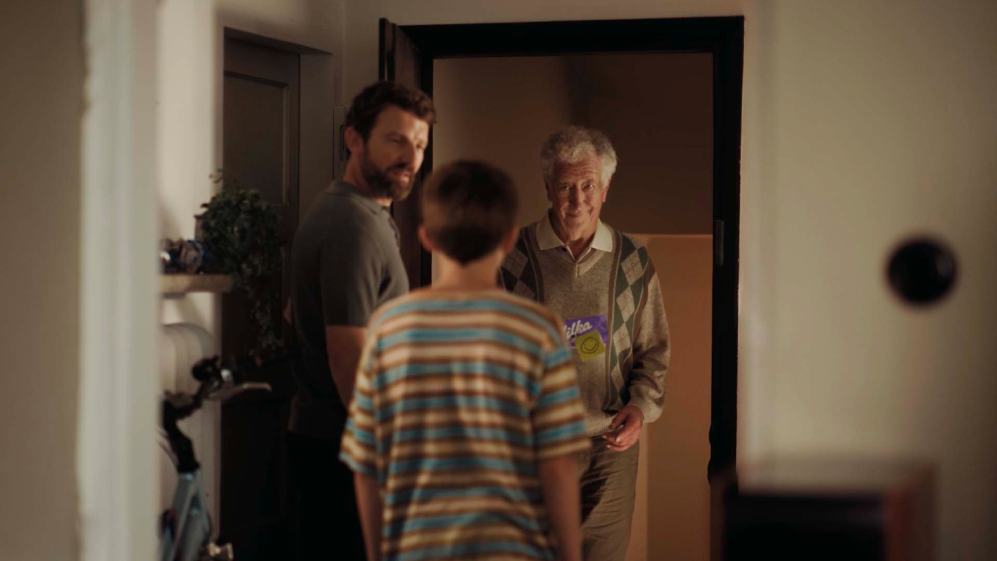 Der ältere Mann besucht den Jungen in seiner Wohnung, in seine Hand die Tafel Schokolade.